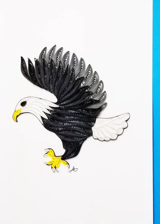 The Card: Eagle Quilling Card 5x7 features a hand-crafted paper quilled bald eagle in flight, with black, white, and yellow strips on a white background and blue border for striking three-dimensional effect.