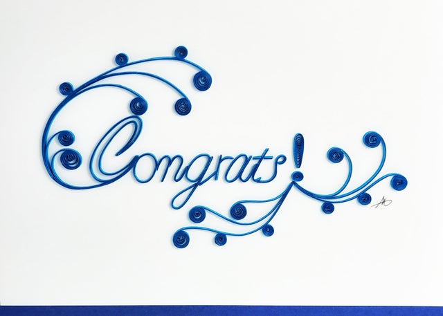 This Sympathy Quilling Card features exquisite handcrafted paper quilling, with blue swirls elegantly forming the word "Congrats!" on a white background.