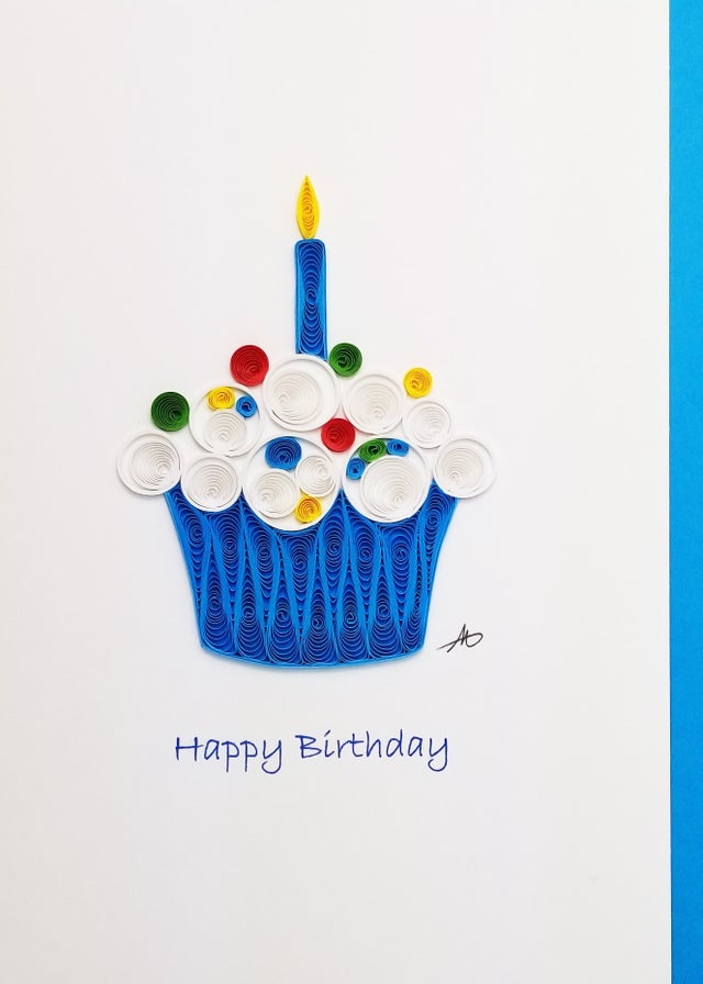 This handmade, locally crafted "Cards: Cupcake Birthday Quilling 5x7" features quilled paper art of a cupcake topped with a candle and surrounded by lively swirls. The phrase "Happy Birthday" is gracefully displayed beneath, perfectly reflecting the celebratory mood.