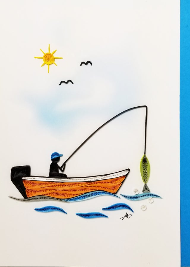 The "Cards: Fishing Boat Quilling" beautifully depicts a tranquil scene of someone on a fishing boat, casting a line under the sun alongside two birds, with intricately quilled fish dancing beneath the blue waves.