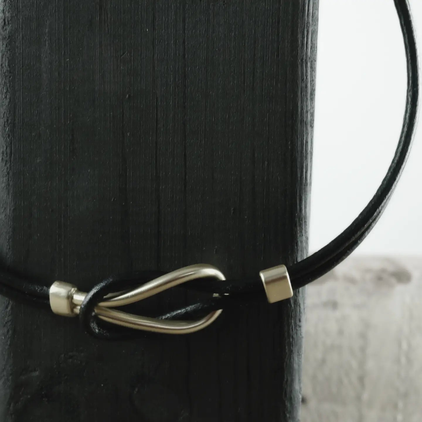 The Necklace: Short Togetherness Leather Necklace Gold Plating rests elegantly on a dark wooden surface.