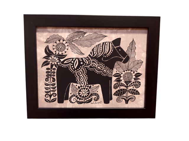 This black-framed artwork features a stylized Dala Horse adorned with decorative patterns, elegantly surrounded by large flowers and leaves; titled Dala Horse with Flowers Framed Batik Artwork, it measures 11x14.