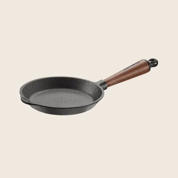 The Skeppshult Skillet with a 7/18cm walnut handle and pre-seasoned surface is elegantly displayed against a plain backdrop, highlighting its excellent heat conduction.