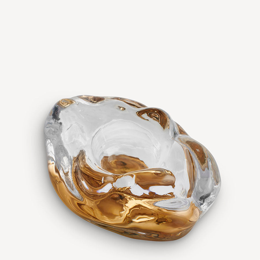 The KostaBoda: Snippan Clear Gold AC-24 is a clear and amber swirl glass bowl with irregular, organic edges, subtly echoing a feminist symbol on a plain background.