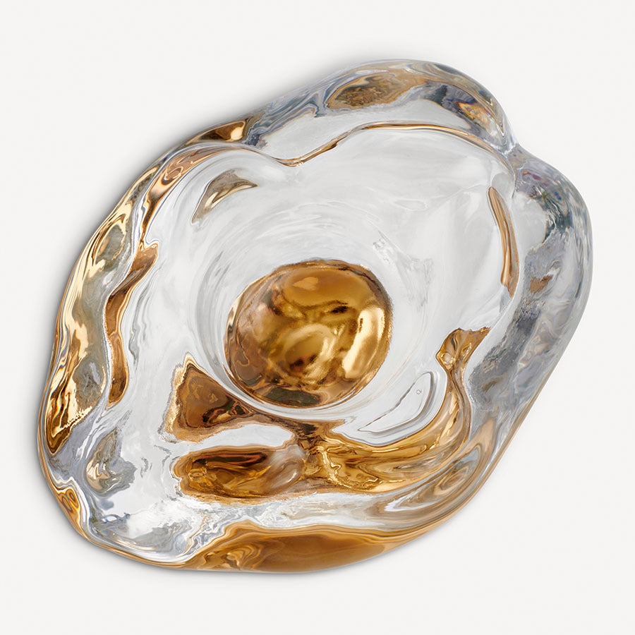 The KostaBoda: Snippan Clear Gold AC-24 is a striking feminist symbol, featuring a clear and gold abstract design with an irregular, organic shape and reflective surface.