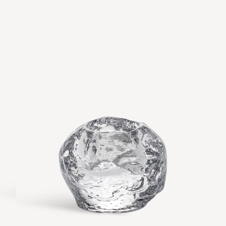 This KostaBoda: Snowball Votive Medium is a clear, irregularly shaped glass piece, reminiscent of Ann Wolffs style with Kosta Boda. Its unique form stands out against a plain white background, capturing the delicate beauty of a snowball frozen in time.