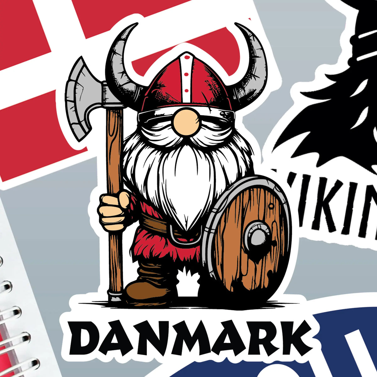 Sticker featuring a cartoon Viking with axe and shield in front of Danish flag labeled DANMARK, with Denmark and Nordic stickers on notebook edges in the background.
