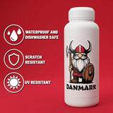 White bottle featuring a Danish Viking gnome sticker and the word “DANMARK”; icons indicate waterproof, dishwasher safe, scratch resistant, and UV resistant on red background.