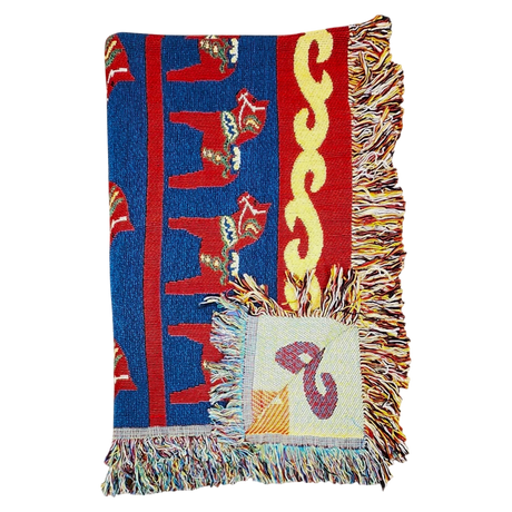 Woven blanket with red, blue, and yellow patterns, Swedish Dala horse designs, multicolored fringes, and a visible square patch.