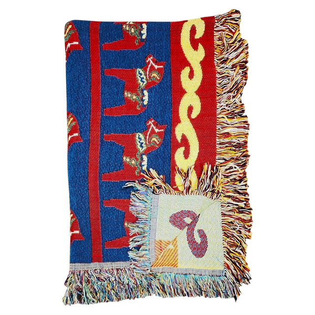 Woven blanket with red, blue, and yellow patterns, Swedish Dala horse designs, multicolored fringes, and a visible square patch.