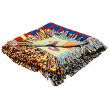 Folded multicolored woven blanket with fringed edges, displaying bright geometric patterns inspired by Scandinavian textiles.