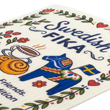 Swedish kitchen cloth featuring FIKA text, a red Dala horse, coffee cup, cinnamon roll, Swedish flag, and colorful flowers arranged in a playful pattern.