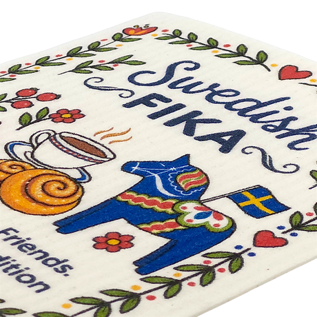 Swedish kitchen cloth featuring FIKA text, a red Dala horse, coffee cup, cinnamon roll, Swedish flag, and colorful flowers arranged in a playful pattern.