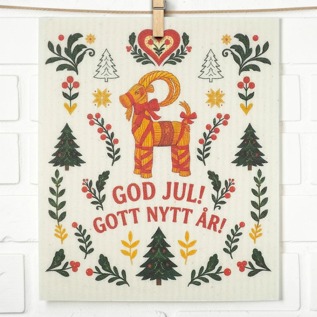 Scandinavian dishcloth with a red and yellow Yule goat, trees, hearts, florals, and Swedish text reading “God Jul! Gott Nytt År!”.