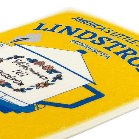 Close-up of a Swedish dishcloth with a floral teapot design and the visible text “Americas Little Sweden” on a bright yellow background.