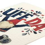 Swedish dishcloth with a gnome holding up “UFF DA” in bold blue and red letters, surrounded by decorative hearts and a coffee pot.