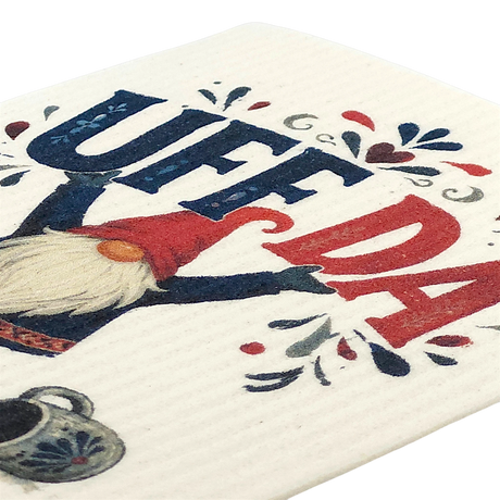 Swedish dishcloth with a gnome holding up “UFF DA” in bold blue and red letters, surrounded by decorative hearts and a coffee pot.