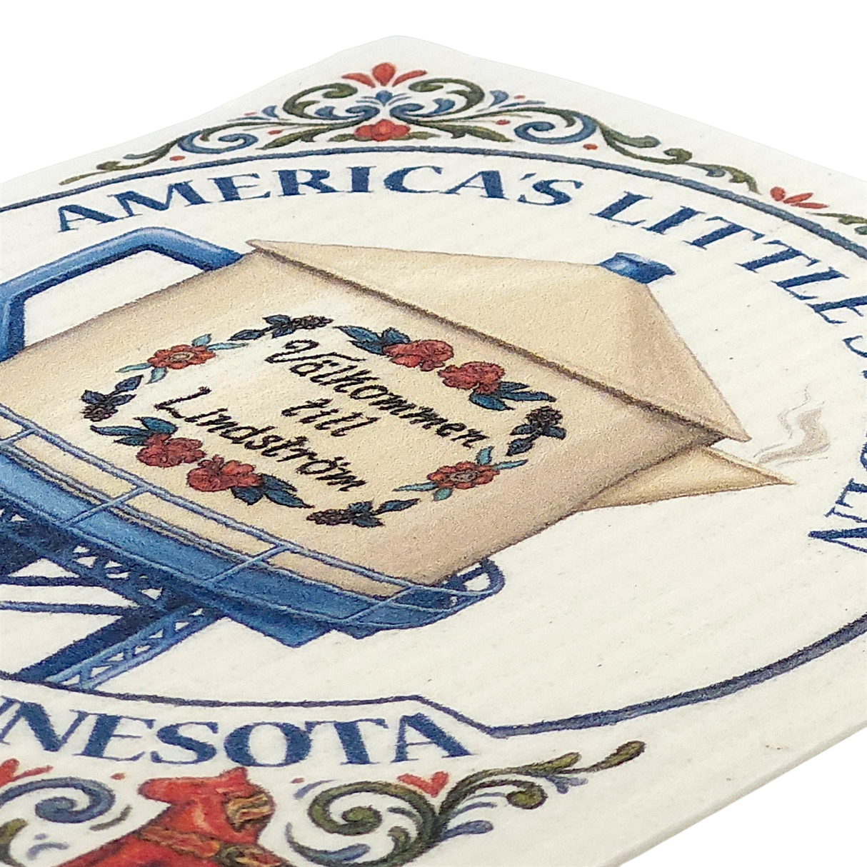 Beige teapot-shaped water tower with floral accents, partial text “AMERICAS LITTLEST,” and a Swedish dishcloth displayed next to it.