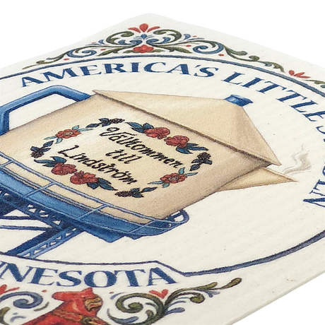 Beige teapot-shaped water tower with floral accents, partial text “AMERICAS LITTLEST,” and a Swedish dishcloth displayed next to it.