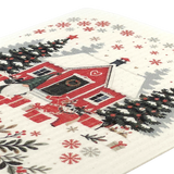 Eco-friendly dishcloth with a red house, snow-covered trees, wrapped gifts, and snowflakes in a Scandinavian winter design.
