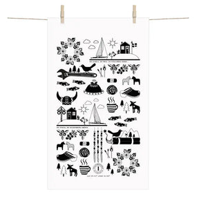 The Made in Sweden Terry-Cotton Towel by Anneko Design Sweden, featuring black Scandinavian-style illustrations on white cotton, including birds, trees, houses, and the iconic Dala horse, hangs on a clothesline with wooden clothespins.
