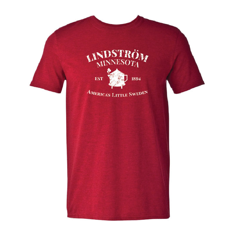 The Tee: Lindstrom Minnesota EST 1894 - Americas Little Sweden is a red tee featuring white Lindström Minnesota Est 1894 text, a Minnesota graphic with a heart, and design elements celebrating the city’s Swedish heritage.