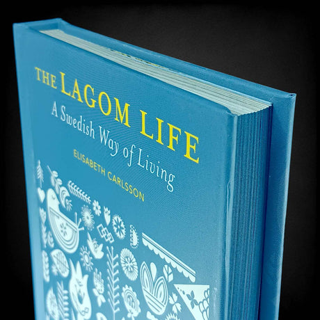 A blue hardcover copy of "The Lagom Life: A Swedish Way of Living" by Elisabeth Carlsson explores the Swedish lifestyle and secrets to work-life balance.