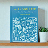 A Book: The Lagom Life: A Swedish Way of Living by Elisabeth Carlsson stands upright beside a small potted succulent.