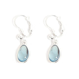 Introducing the Earrings: Glass Drop Blue A&C Norway French Clip, a stunning pair of silver-plated earrings adorned with hand-ground blue glass pendants set against a white backdrop.