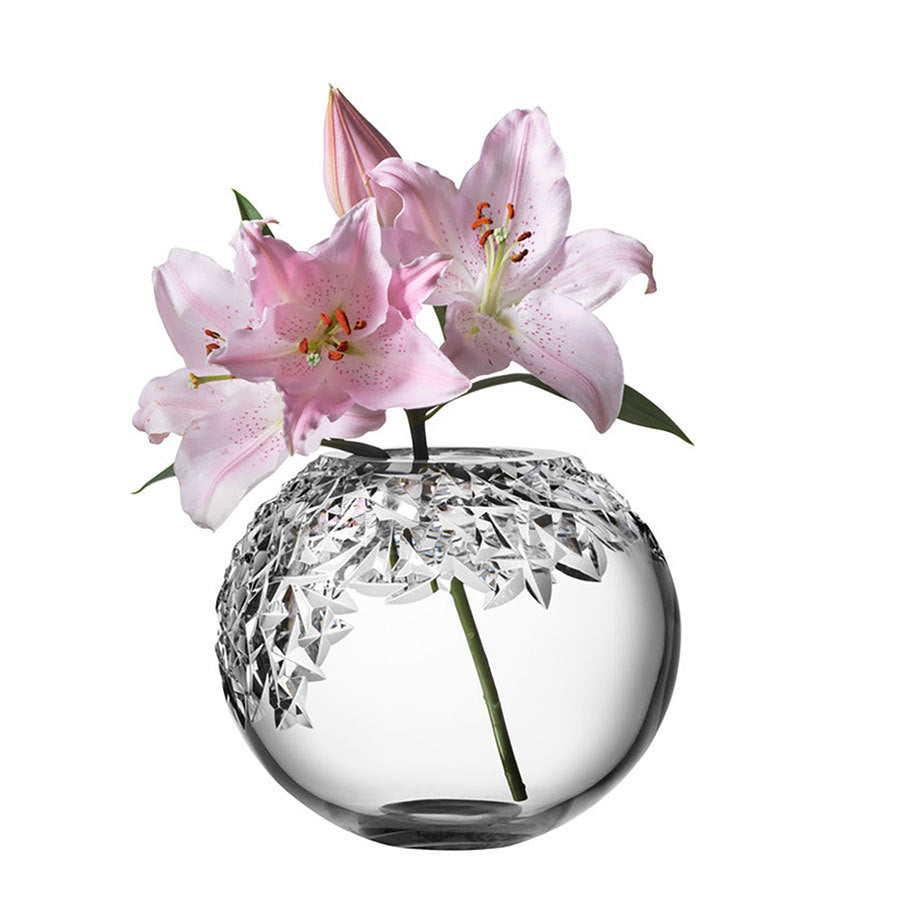 The Orrefors: Carat Globe Vase XL, adorned with pink lilies, including blooms and a bud, is set against a plain white background.