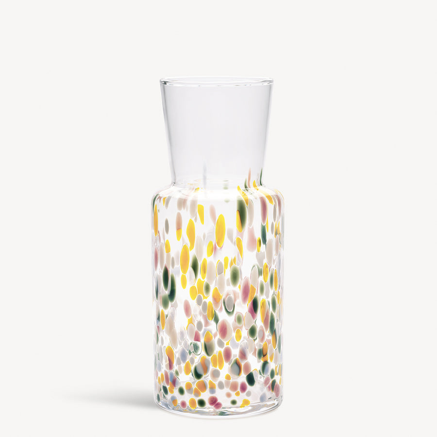 The KostaBoda: Meadow Vase Spring Tall, designed by Sara Persson, is a clear glass vase with a cylindrical body and narrow neck, adorned with vibrant yellow, green, and pink spots inspired by natures palette.