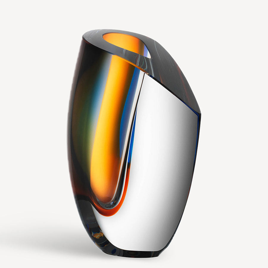 Introducing the KostaBoda: Mirage Blue/Amber Vase Large from the Artist Collection. This exquisite abstract piece by Göran Wärff features a captivating curved design with vibrant shades of orange, yellow, and dark reflective surfaces.