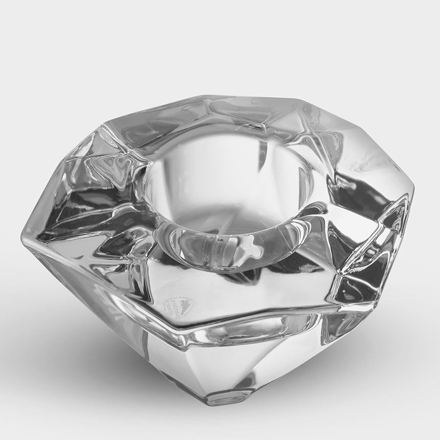 An Orrefors: Precious Votive Candle Holder, with its faceted clear glass and geometric design, elegantly rests on a white surface.