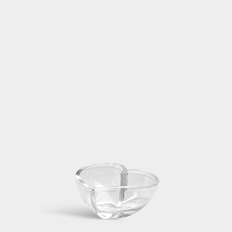 A small Orrefors Heart Bowl/Votive, with two distinct curved sections resembling a figure-eight, elegantly stands against a plain white background.