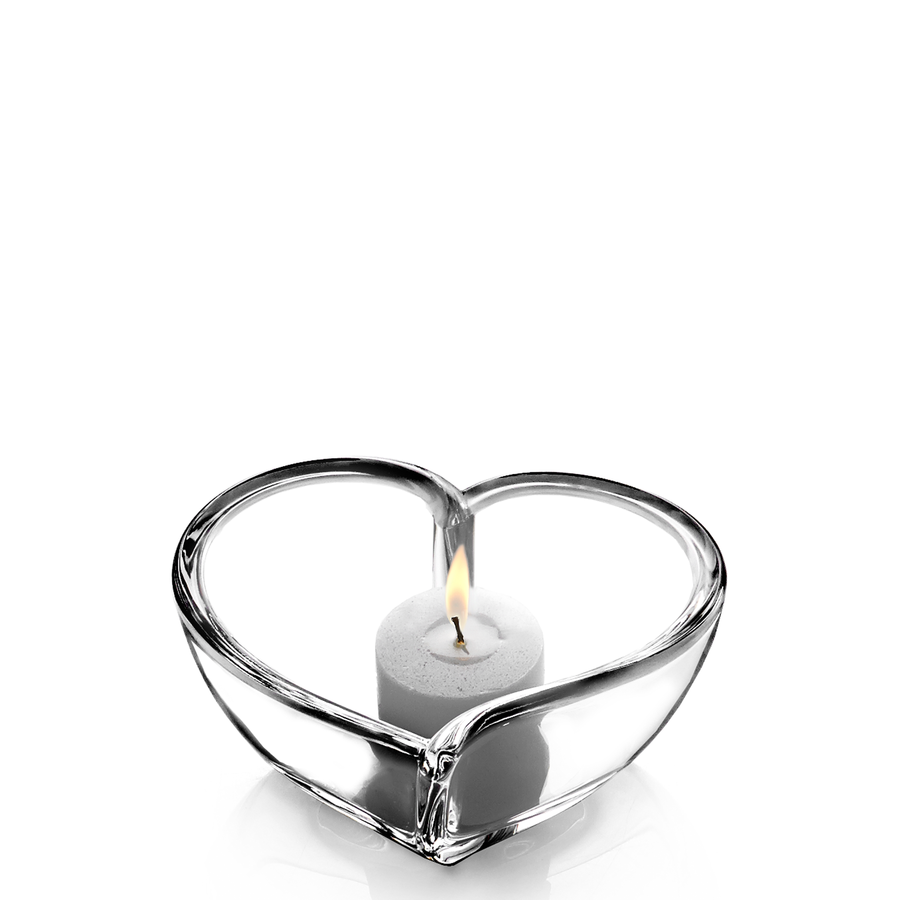 A small lit candle rests elegantly in the Orrefors Heart Votive Small, against a pristine white background.