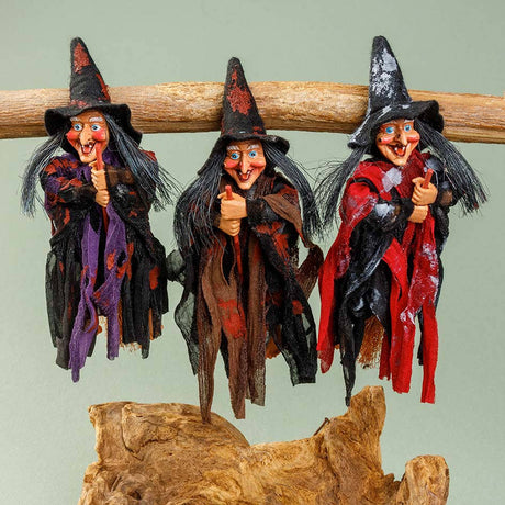 The Walburga Red Kitchen Witch Doll features a pointed hat and vibrant tattered clothes, giving a thumbs-up gesture as a playful handmade good luck charm from Germany.