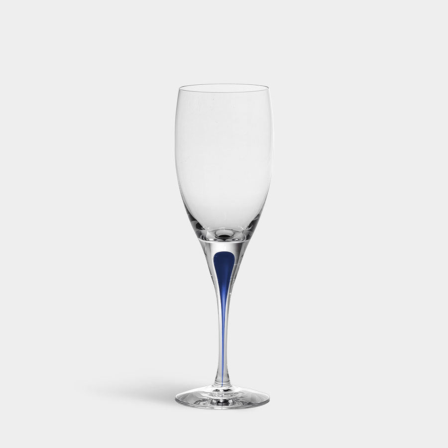 The Orrefors Intermezzo Blue White Wine Glass, 6oz, features a clear flute and a blue-tinted stem, echoing Erika Lagerbielke’s iconic design against a white background.