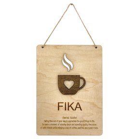 Wooden plaque with a steaming cup cutout, heart detail, and the word “FIKA” in bold letters, referencing the Swedish coffee break tradition.