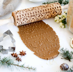 The Rolling Pin: Reindeer Birds & Trees Embossing Rolling Pin, inspired by Scandinavian design and handmade craftsmanship, skillfully embosses gingerbread dough with detailed snowflake and Christmas deer patterns amidst a selection of festive cookie cutters and decorations.