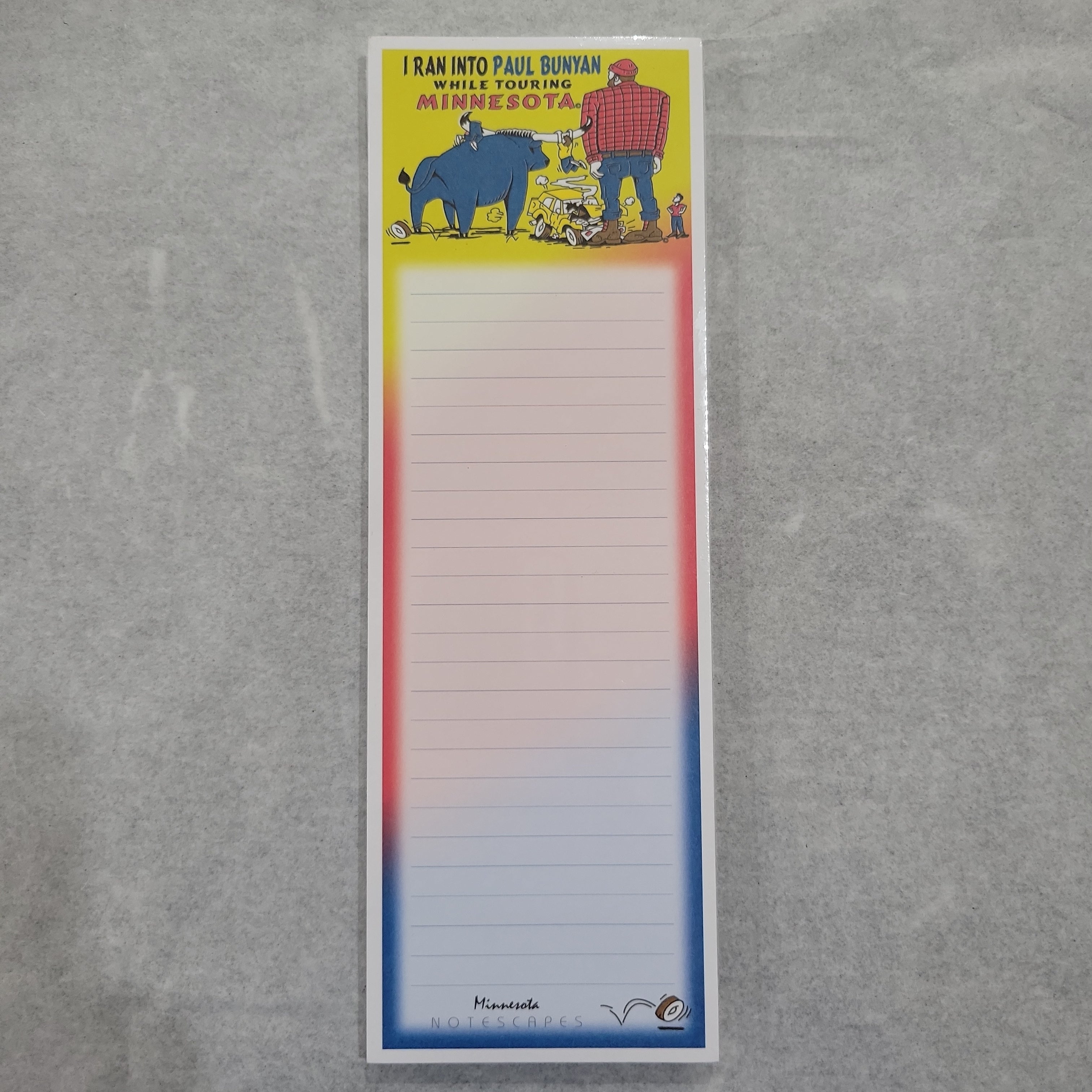 Introducing the Tablet: Ran into Paul Bunyan Notepad—featuring a whimsical illustration of a humorous Paul Bunyan and his blue ox atop lined pages. With its sturdy cardboard back, this colorful notepad is both fun and functional for jotting down your thoughts.