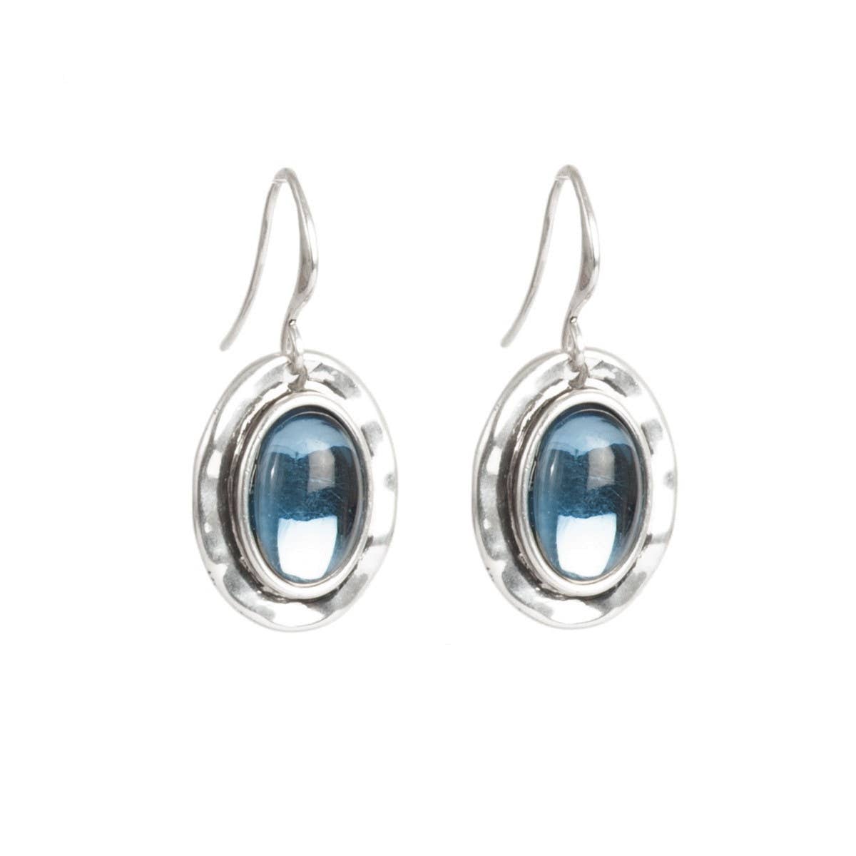 The Earrings: Silver Deep Blue Hanging Earrings take inspiration from Scandinavian design, showcasing captivating blue gemstone centers and elegant hook clasps in their oval silver form.