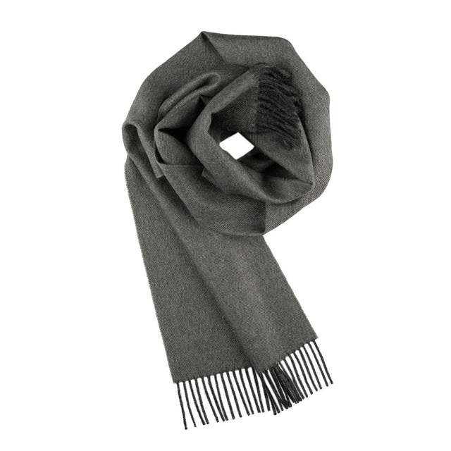 The 100% Baby Alpaca Scarf in Carbon (Charcoal) is shown folded with fringed ends on a white background, highlighting its soft texture and unisex appeal for any wardrobe.