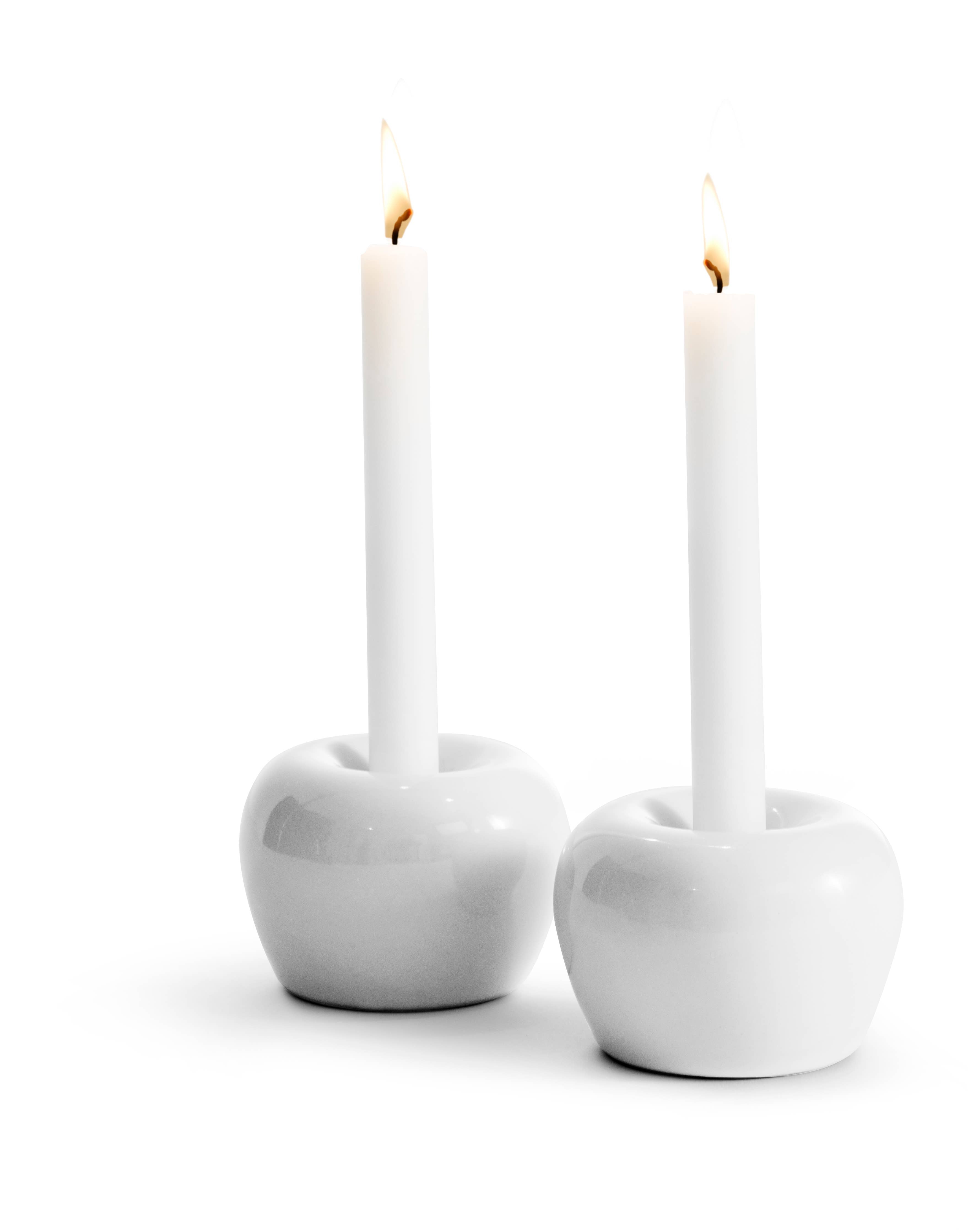 A pair of lit white candles sit gracefully in round, glossy Candle Holder: White 2-Pack Mini Apple stoneware on a plain background, highlighting the minimalist craftsmanship emblematic of Sweden.