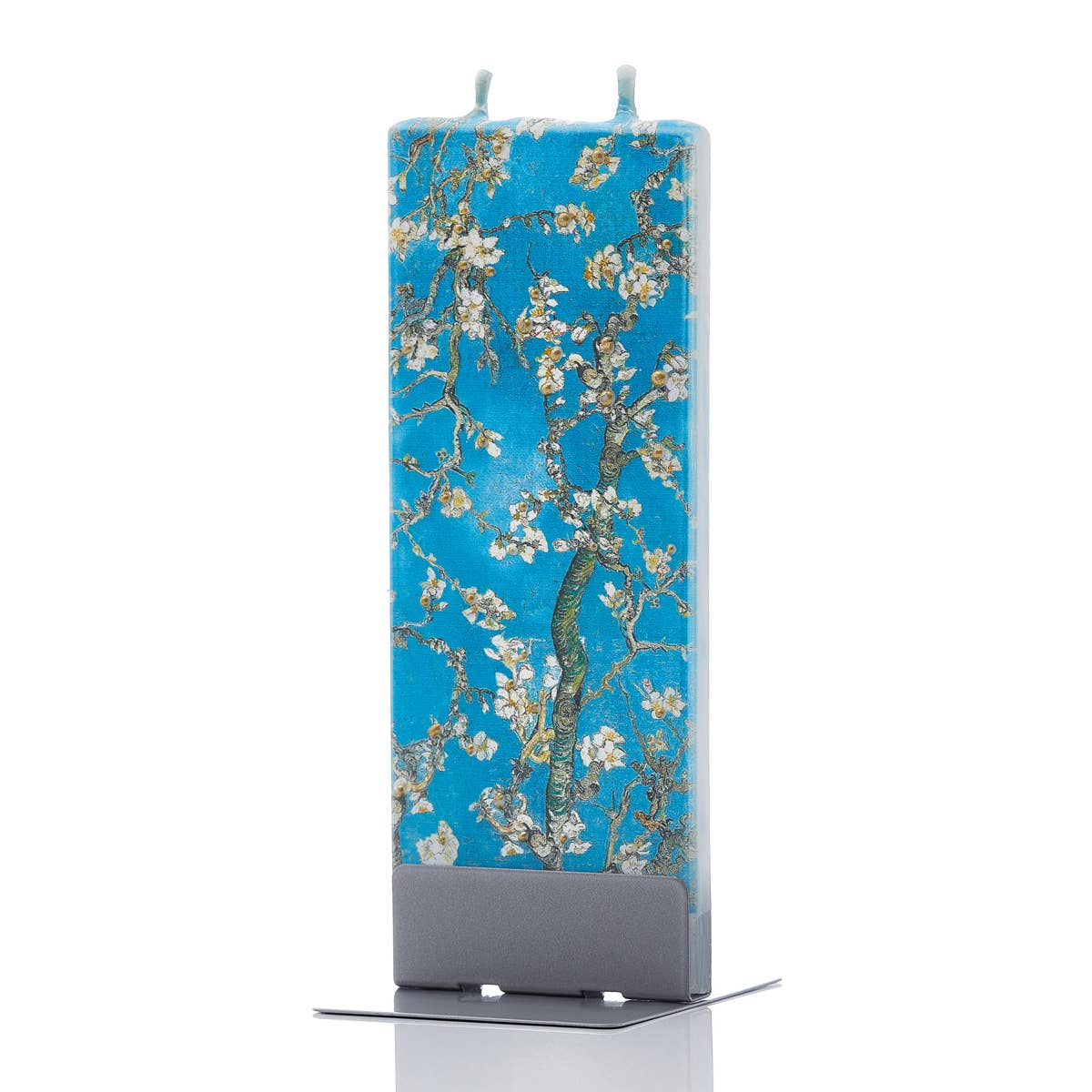 A flat candle with a subtle blue background features the Van Gogh Almond Blossom design, depicting white blossoms on branches, elegantly displayed on a metallic stand.