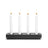 Four lit white candles rest elegantly on the dark rectangular Stumpastaken Black Powder Coat Swedish Candle Holder, crafted by Jonas Torstensson from recycled aluminum.