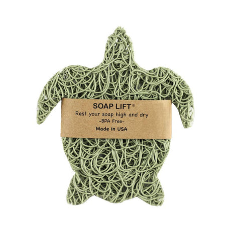 The Soap Lift: Soap Saver Sea Turtle - Sage is a turtle-shaped, sage-colored bioplastic soap lift featuring a brown paper label. It is designed to keep your soap dry and extend its lifespan. This BPA-free product is made in the USA.