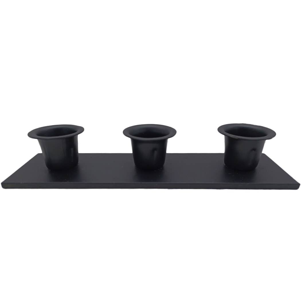 The Candle Holder: Triple Wrought Iron Taper Holder serves as a sleek and modern centerpiece, with three identical black containers evenly arranged on a black rectangular tray. It's perfect for displaying minimalist candle designs or adding style to your decor.