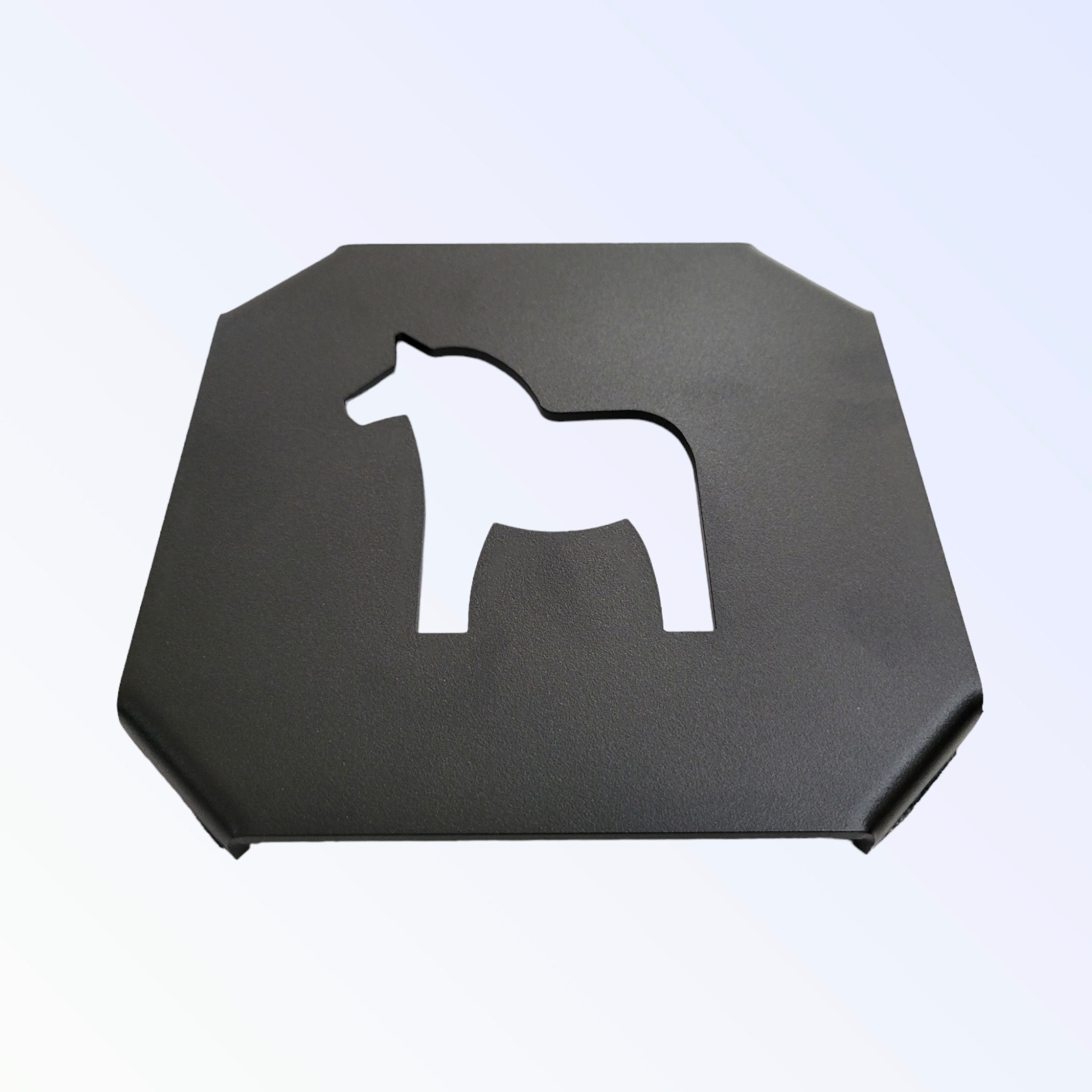 Black metal trivet featuring a horse-shaped cutout, inspired by a Swedish Dala horse, set against a light gradient background.