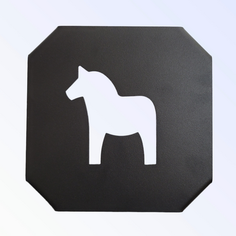 A black cast iron trivet features a white silhouette of a Swedish Dala Horse.