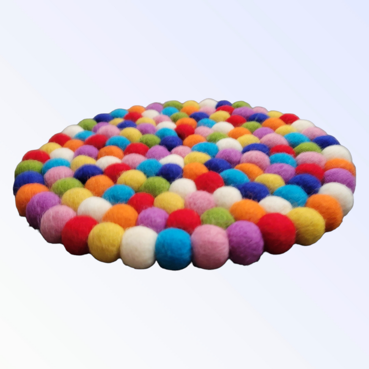 The Trivet: Multi-Color Round Wool Felted Pom-Pom Trivet is a circular mat made from vibrant wool felt balls, forming a delightful pattern on a light background, adding charm and functionality to any kitchen.